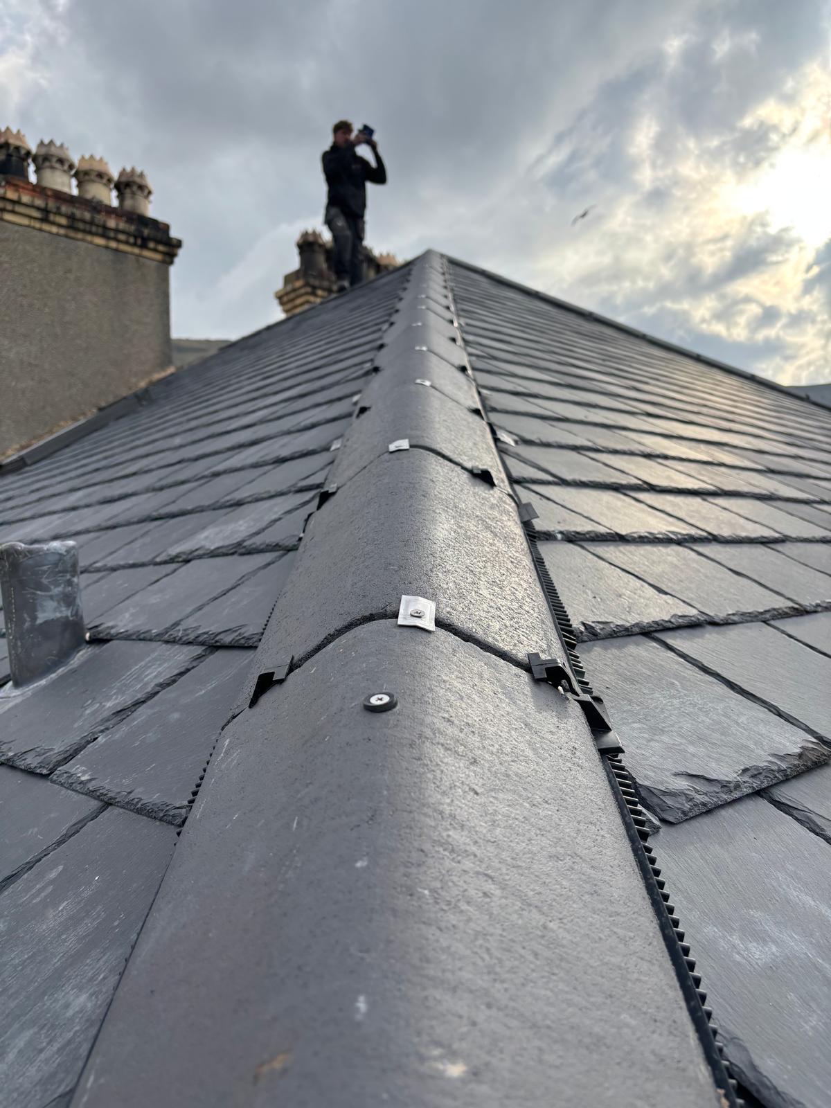 Completed natural slate roof with neat ridge tiles and lead detailing