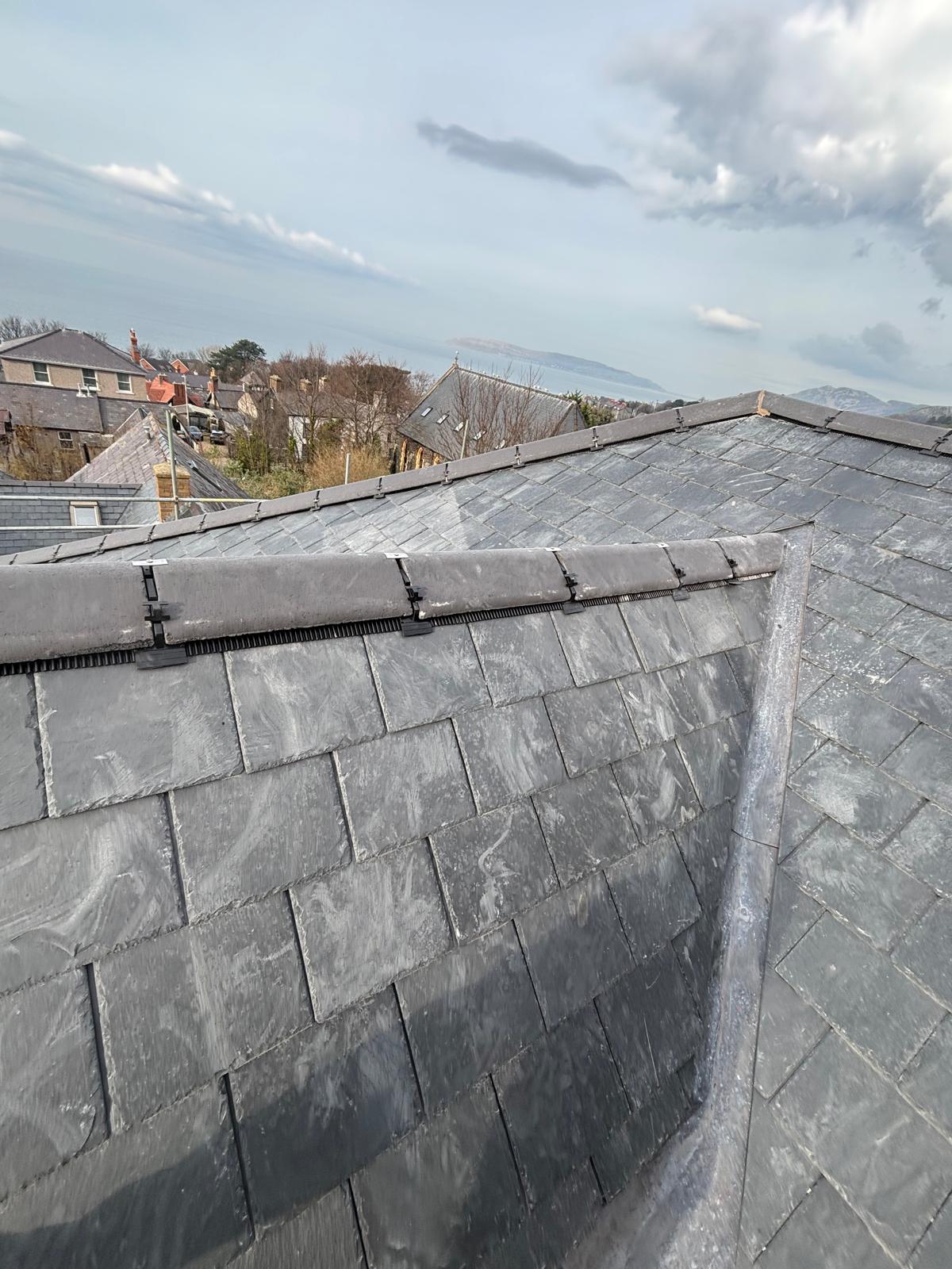 Completed natural slate roof with neat ridge tiles and lead detailing near Anglesey