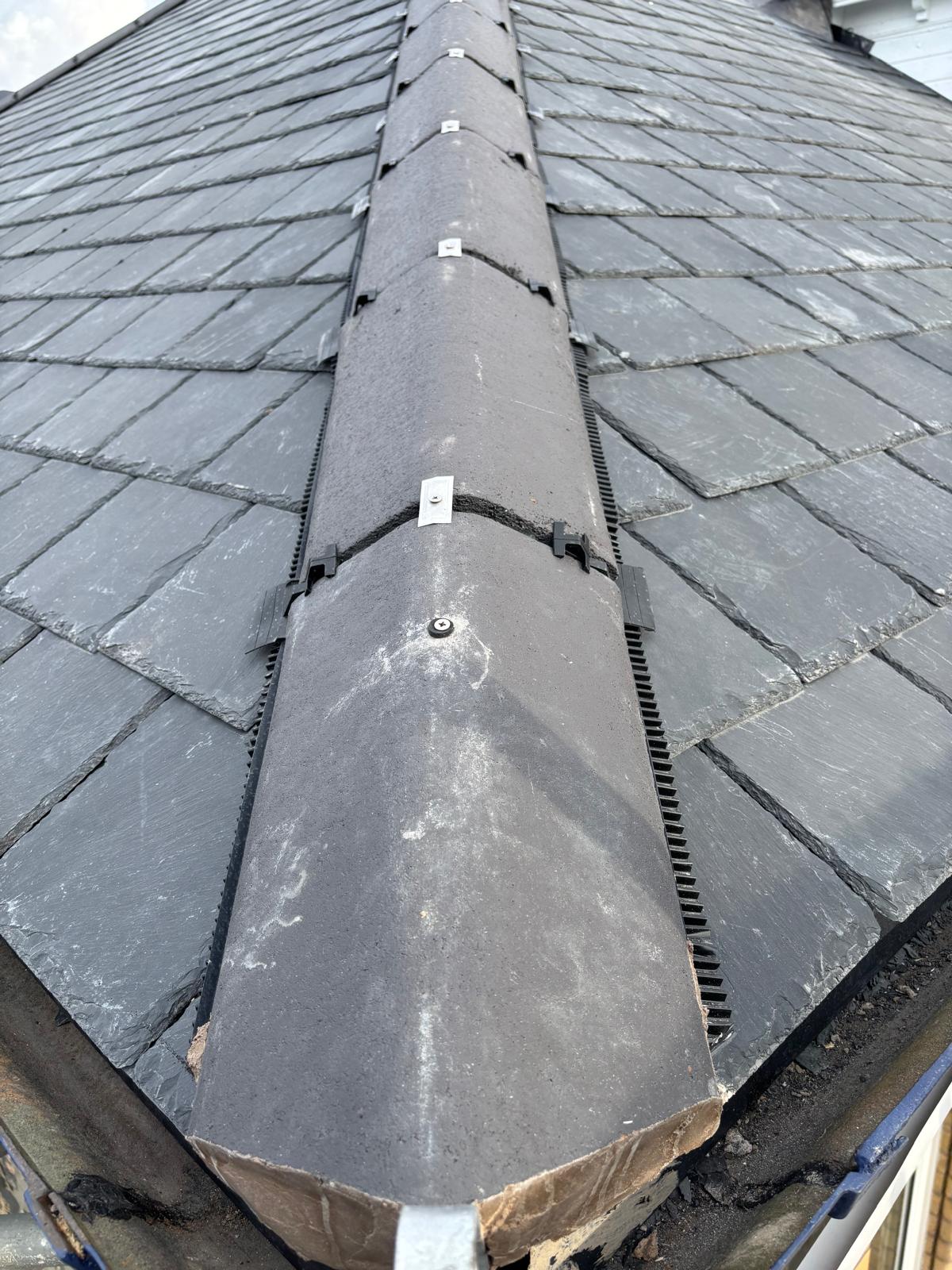 Completed natural slate roof with neat ridge tiles and lead detailing